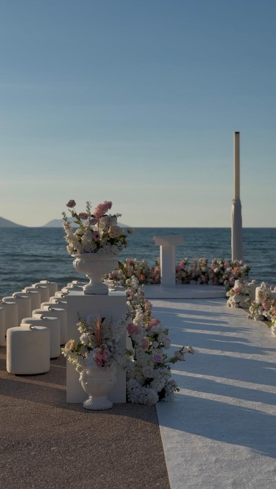 Bojo Resort Orikum — minimalistischer Zeremonie-Gang direkt am Meer mit floralen Urnen