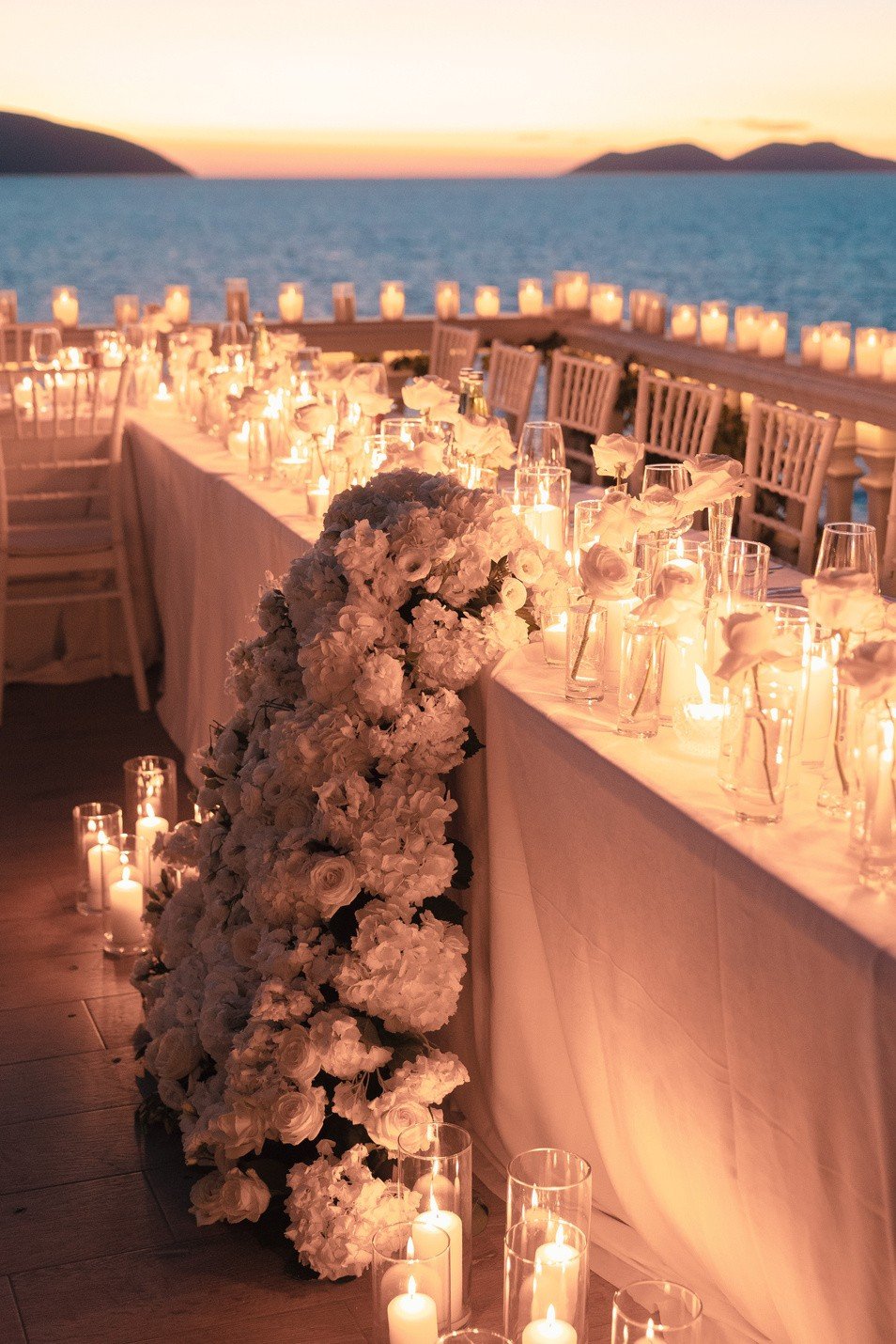 Festtafel mit Blumen bei Sonnenuntergang am Meer